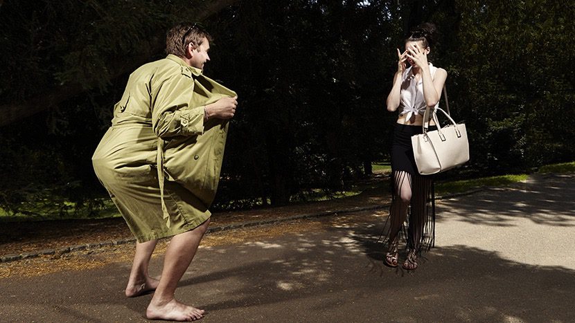 Muškarac u zelenom kaputu pokušava da uhoći ženu na ulici, dok se ona brani i skriva lice.